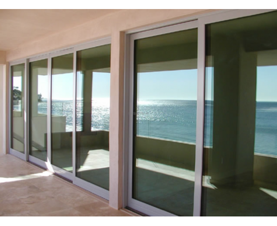 Bīdāmās ārdurvis izveidotas no alumīnija profiliem un stikla paketēm ēkas fasādē