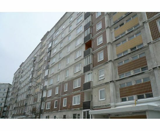 Daudzdzīvokļu ēkas fasāde slīpumā ar plastikāta un koka logiem.