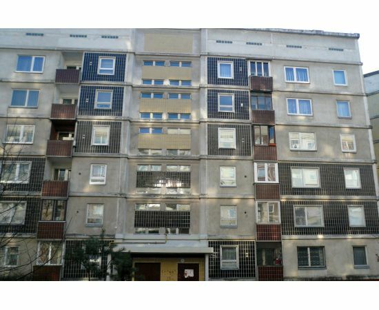 Daudzdzīvokļu ēkas fasāde priekšskatā ar plastikāta un koka logiem