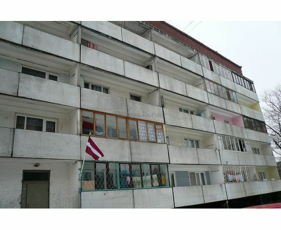 "Mazģimenes" daudzdzīvokļu mājas fasāde ar dažādiem logiem un balkoniem renovācijas vajadzībām.